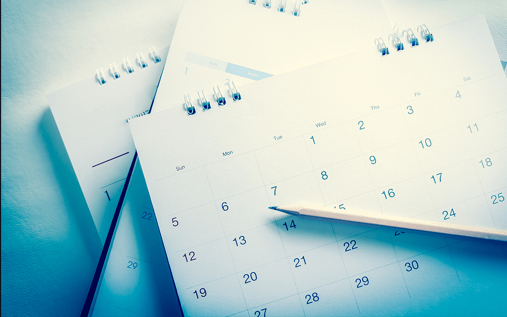 A pile of calendars and a pencil.